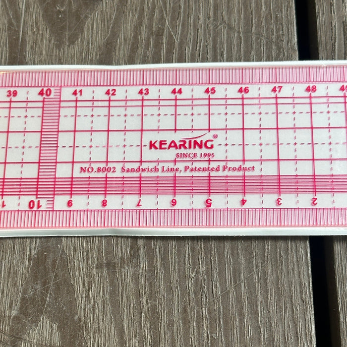 A Kearing No. 8002 Sandwich Line ruler, made of clear plastic with red printed measurement markings and text.
KEARING brand, No 8002, Clear Plastic Straight Ruler, 50cm x 5cm